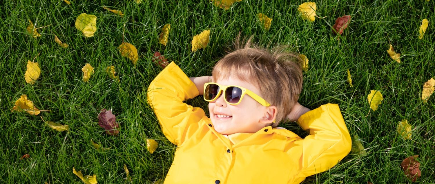kid in raincoat on green grass